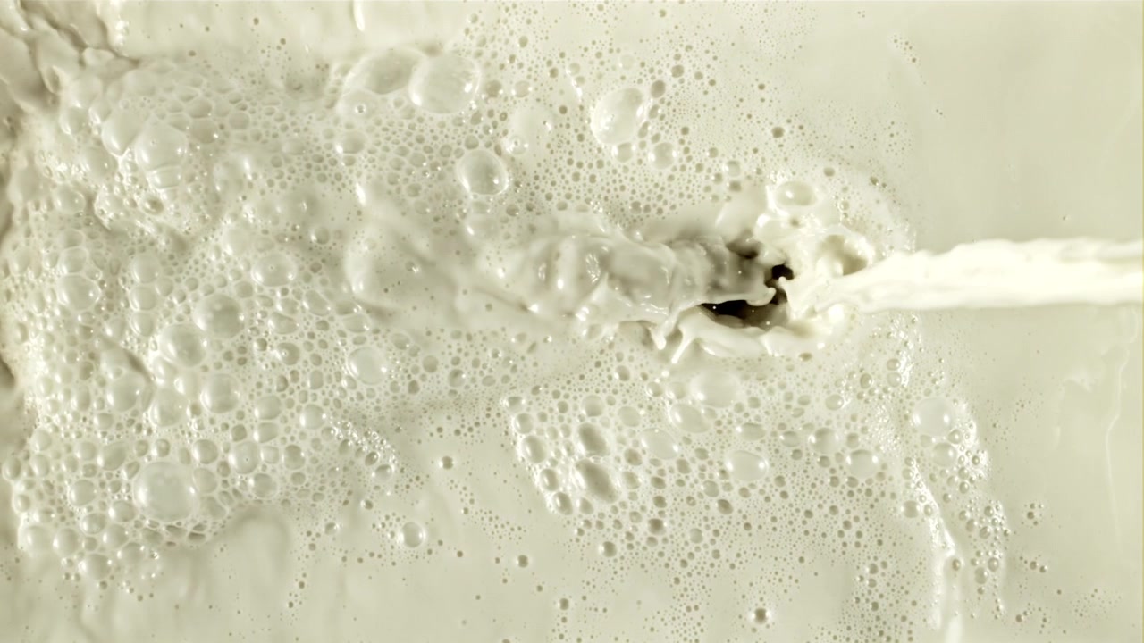 Versamento al rallentatore di latte bianco cremoso con bollicine