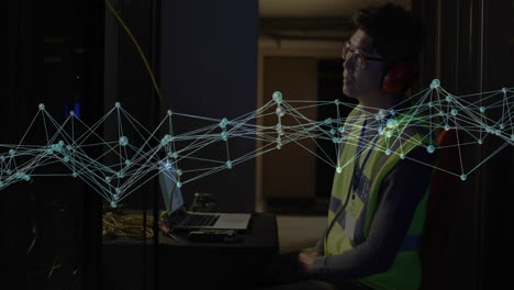 IT technician monitoring technology server rack, laptop wearing safety vest, floating network graph