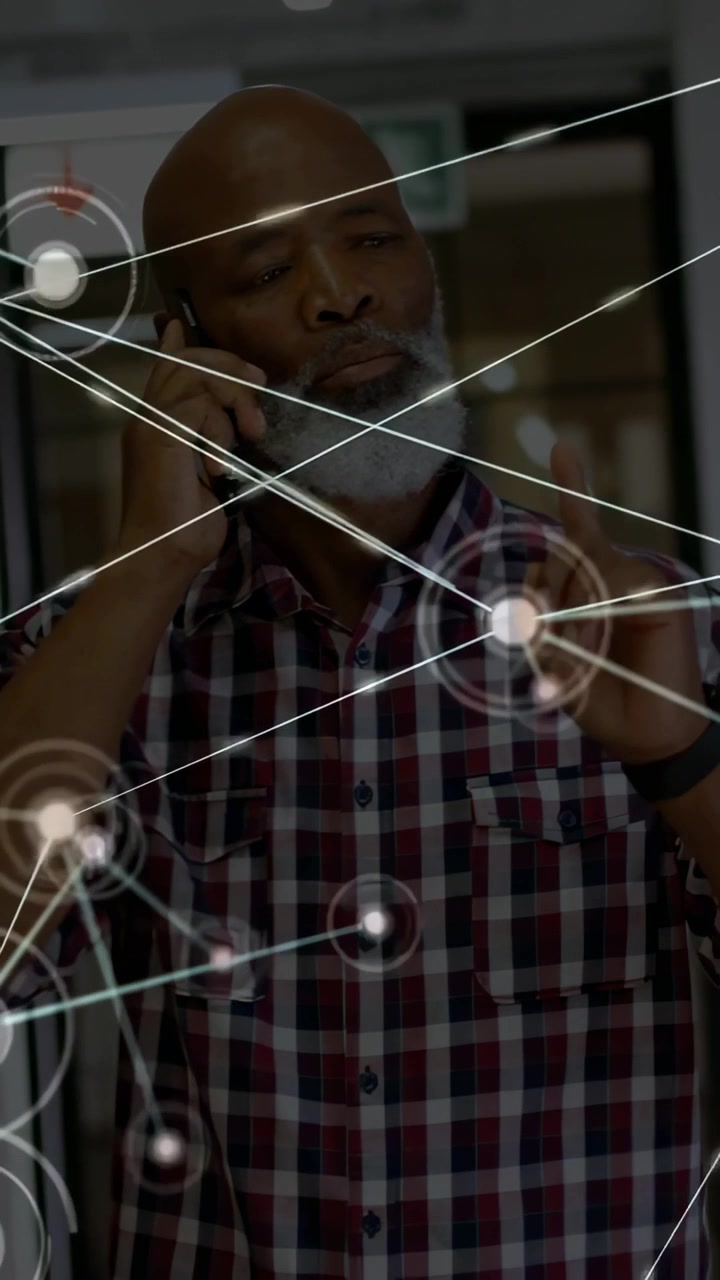 African American man holding smartphone to ear and pointing at holographic nodes in corridor