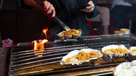 oysters being grilled with flames and smoke