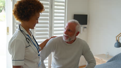 female nurse wearing uniform meeting with senior male patient in private hospital room