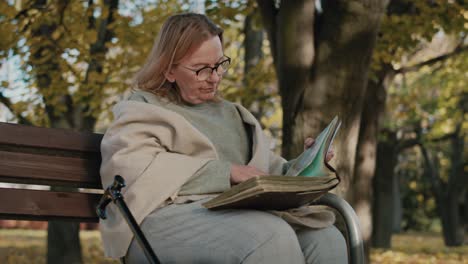 senior woman sitting on bench and looking at old photographies