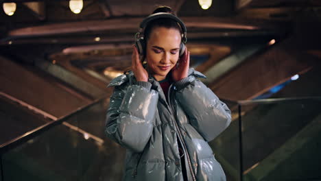 girl enjoy song headphones standing at urban backdrop. woman listening music.