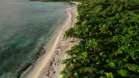 aerial rotating view of remote, uninhabited tropical island with turquoise water and dense forest in spain