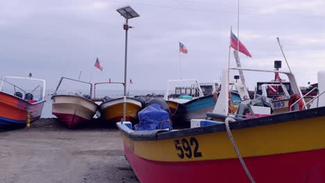 wooden fishing boats with flags of chile in storage lot on ocean coast