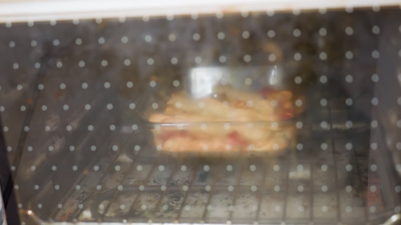 점선 오븐 문을 통해 클로즈업한 장면에서 트레이에 반죽이 구워지고, 열기로 아른거리고, 황금빛 빵 껍질이 형성되고, 기기 내부에서 김이 소용돌이치고, 흐릿한 주방 내부가 보이고, 따뜻한 홈메이드 페이스트리가 보여요.