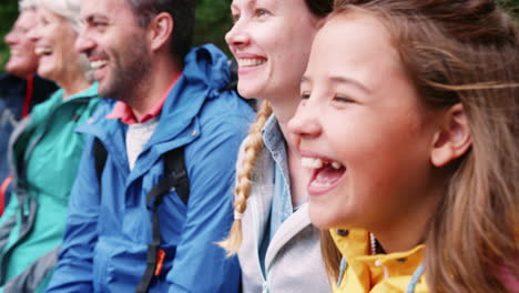 camera moving in slow motion along multi generation family sitting in a row laughing, head and shoulders, close up, lake district, uk