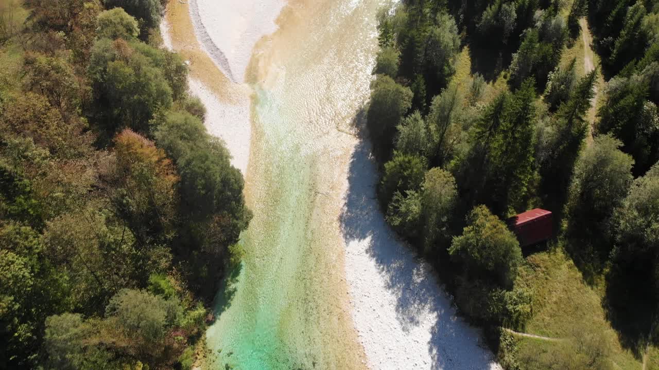 Vista dall'alto di un pescatore che cammina in un fiume basso color smeraldo in cerca di pesce, ripresa aerea di pesca in una giornata estiva molto luminosa e soleggiata, fiume Isonzo, Slovenia