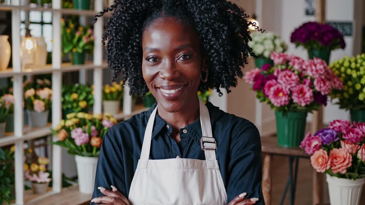 A florist in an apron smiles confidently at the camera. The video captures her from a medium angle