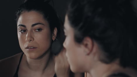 primer plano, de, mujer joven, aplicar maquillaje, con, cepillo, delante de, un, espejo