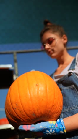 mujer sosteniendo una gran calabaza