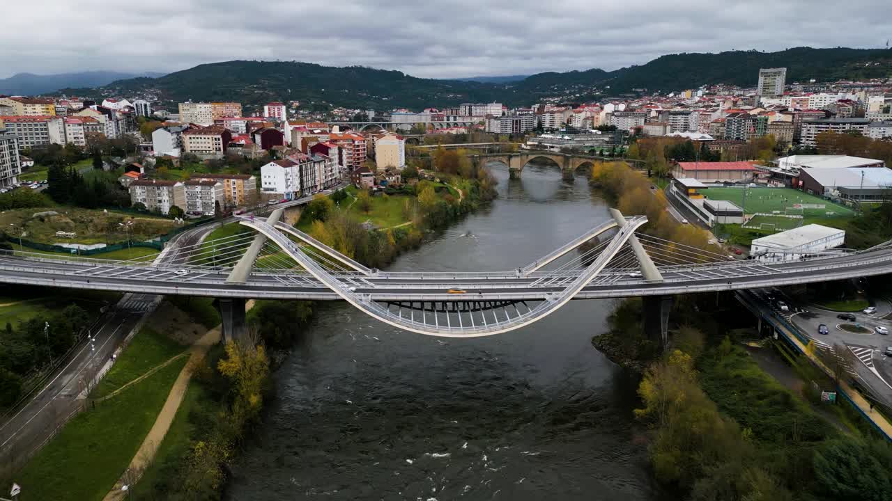 Grassy green lawns and Roman bridge behind Millennium Bridge Mi&ntilde;o River in Ourense, Galicia, Spain