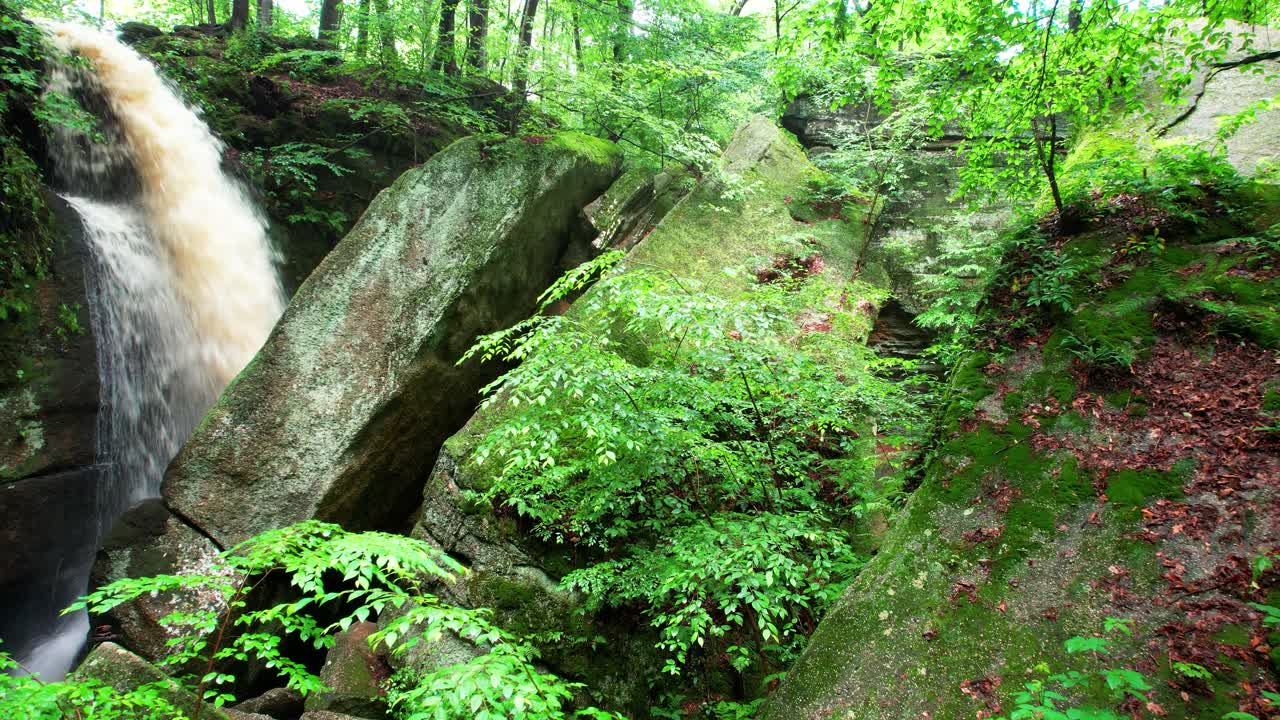 una vista cinematográfica de la cascada cae entre hojas y rocas cubiertas de musgo en el parque estatal nelson ledges en un hermoso día de otoño