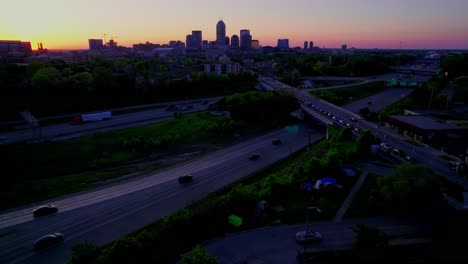 moody aerial twilight shot of a homeless tent encampment adjacent to a suburban indianapolis highway—ideal for social impact and documentary b-roll.