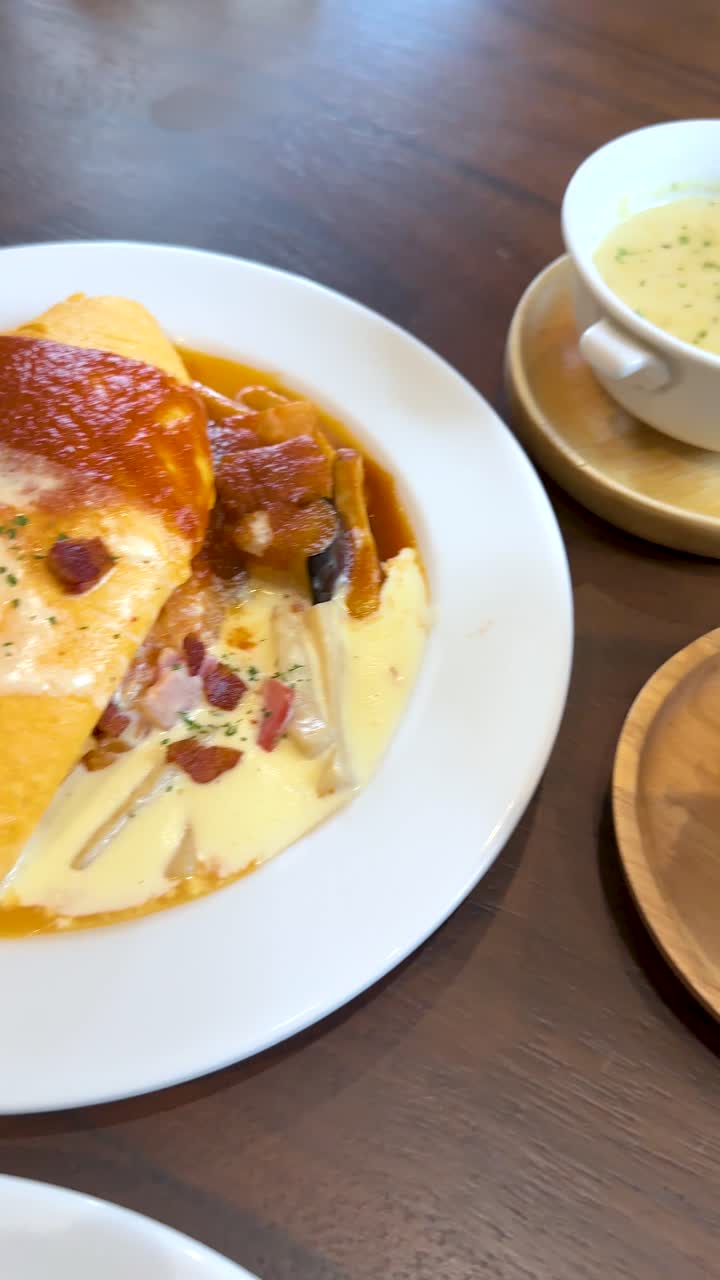 Omurice de curry japonés, ensalada y sopa sobre mesa de madera, iluminación natural brillante, paneo de cámara suave