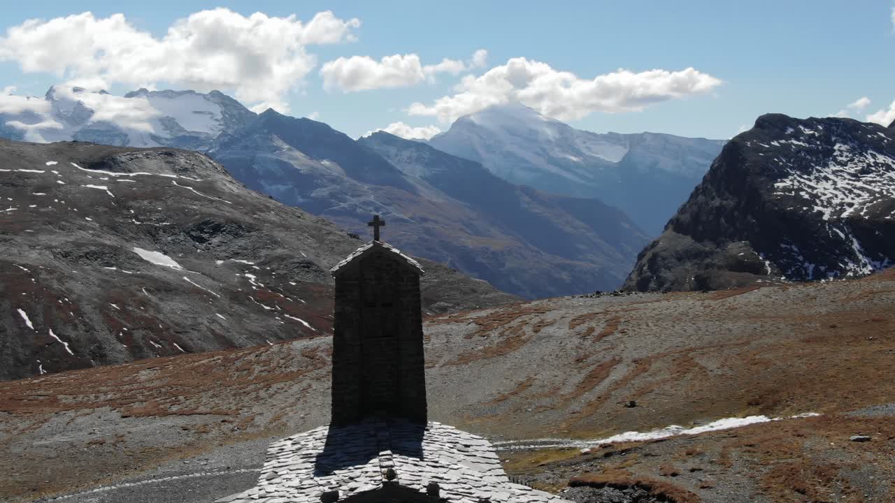campanario de una pequeña iglesia de piedra en el puerto de montaña col de l'iseran con un paisaje impresionante en el fondo, francia