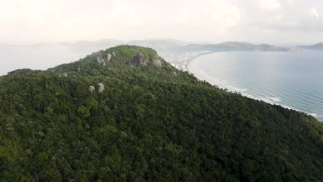 Drone-Distanciando-Una-Hermosa-Montaña-De-Bosque-Tropical-Con-Una-Playa-Paradisíaca-Detrás-En-Un-Día-De-Verano