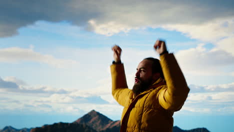 hiker dressed in warm outdoor gear celebrates reaching the top of a mountain