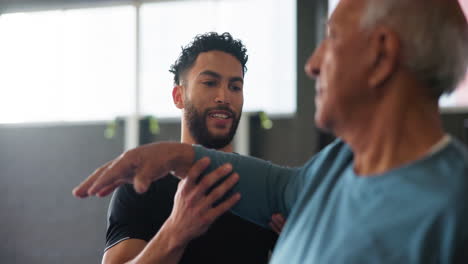 personal trainer helping senior man exercise