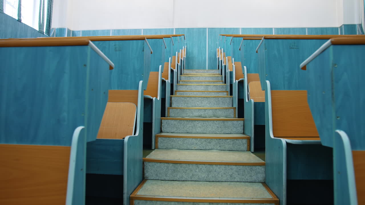 Empty auditorium. Stairs between two rows of desks in conference hall. Beautiful class for studying without students. Classroom in the university with wooden desks.