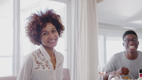 portrait of young friends sitting around table at home enjoying meal together