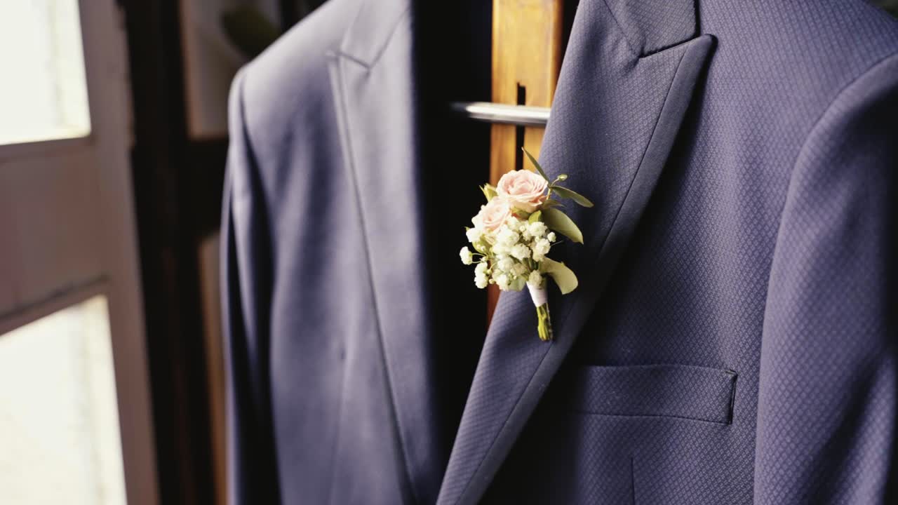 un ramo de flores decorativas colgando de la chaqueta del novio de una boda