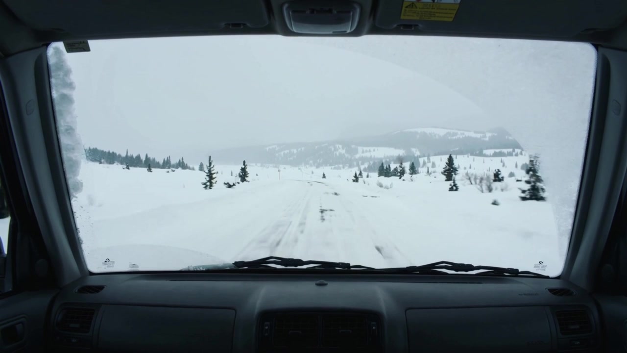Motore che romba, spingendo il veicolo in avanti lungo due solchi verso colline distanti, con parabrezza e tergicristalli.