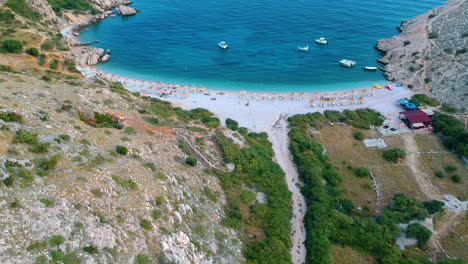 Vista-Aérea-De-La-Playa-De-La-Bahía-De-Oprna-Con-Sombrillas-En-La-Isla-De-Krk,-Croacia