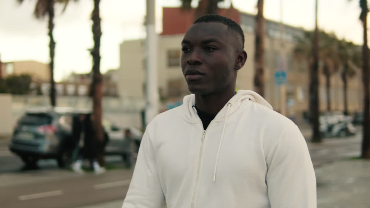 Thoughtful Young Man in White Hoodie on City Street