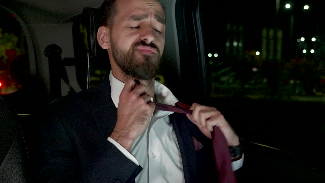 사업가가 그의 럭셔리 차의 뒷좌석에서 여전히 노트북에서 일하고 있습니다.