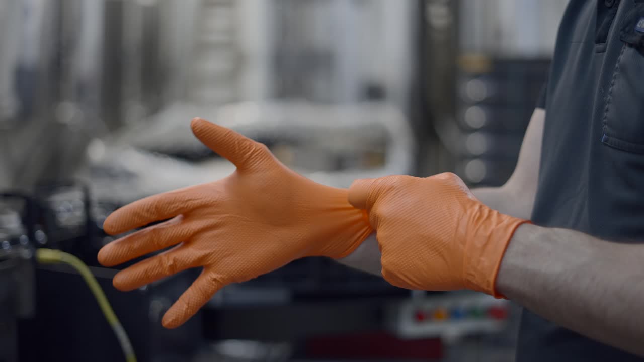 Worker Putting on Orange Protective Gloves