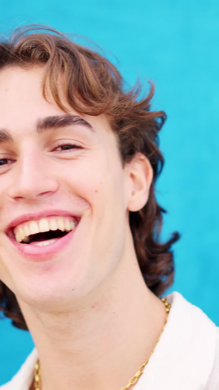 Caucasian young man smiling at camera in a blue background