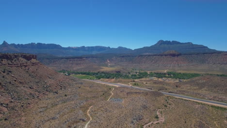 drone shot long road the runs through mount zion with mountain range in the background located in southern utah