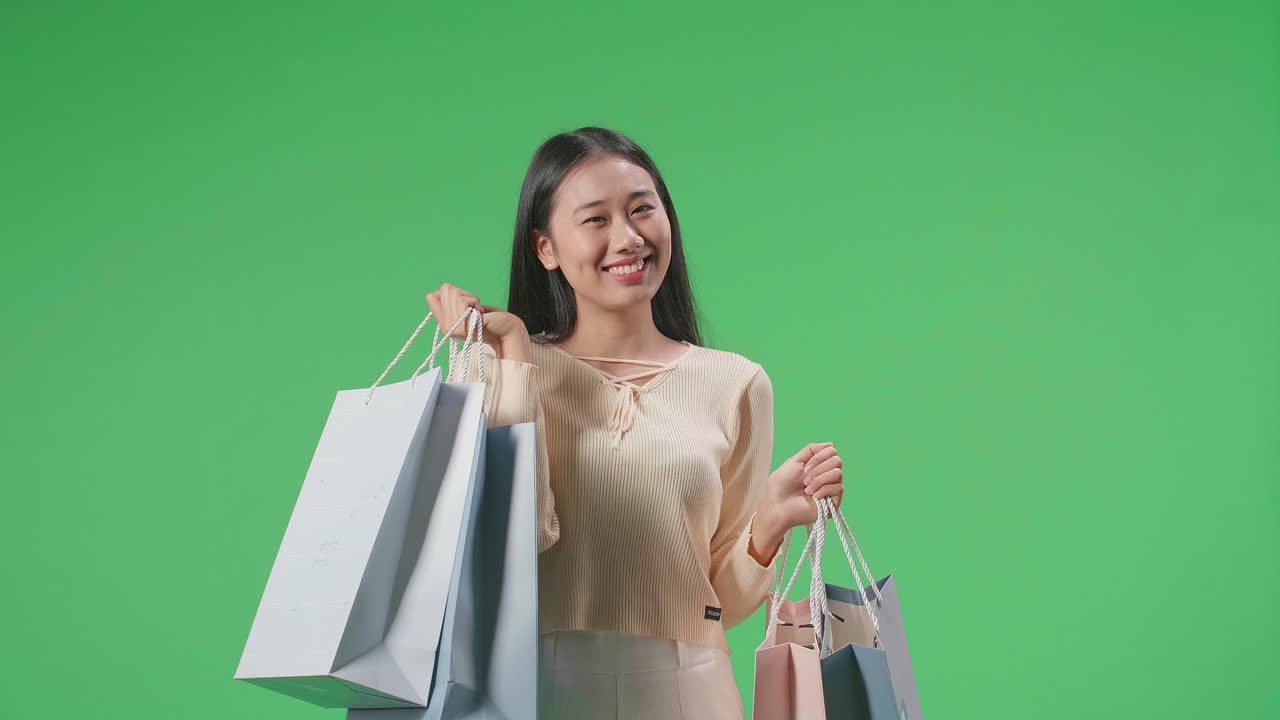 An Asian Shopping Woman With Shopping Bags Smile To Camera While Standing In Front Of Green Screen