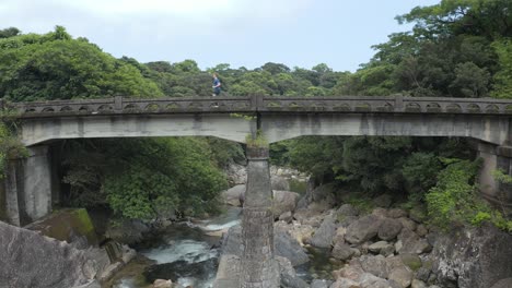 Yakushima-Japan,-Man-running-from-right-to-left-on-Bridge-in-forest