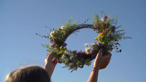 person holding a beautiful floral wreath against a clear blue sky