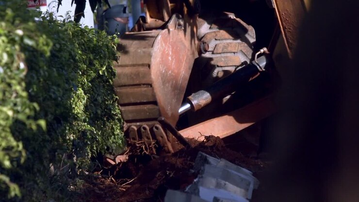 Trattore che scava in un cantiere edile vicino al parco cittadino.