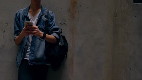 Man-using-mobile-phone-while-leaning-against-wall-4k