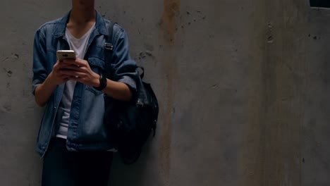 man using mobile phone while leaning against wall 4k