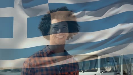 Animation-of-greece-flag-waving-over-smiling-african-american-man-with-afro-hair-enjoying-at-beach