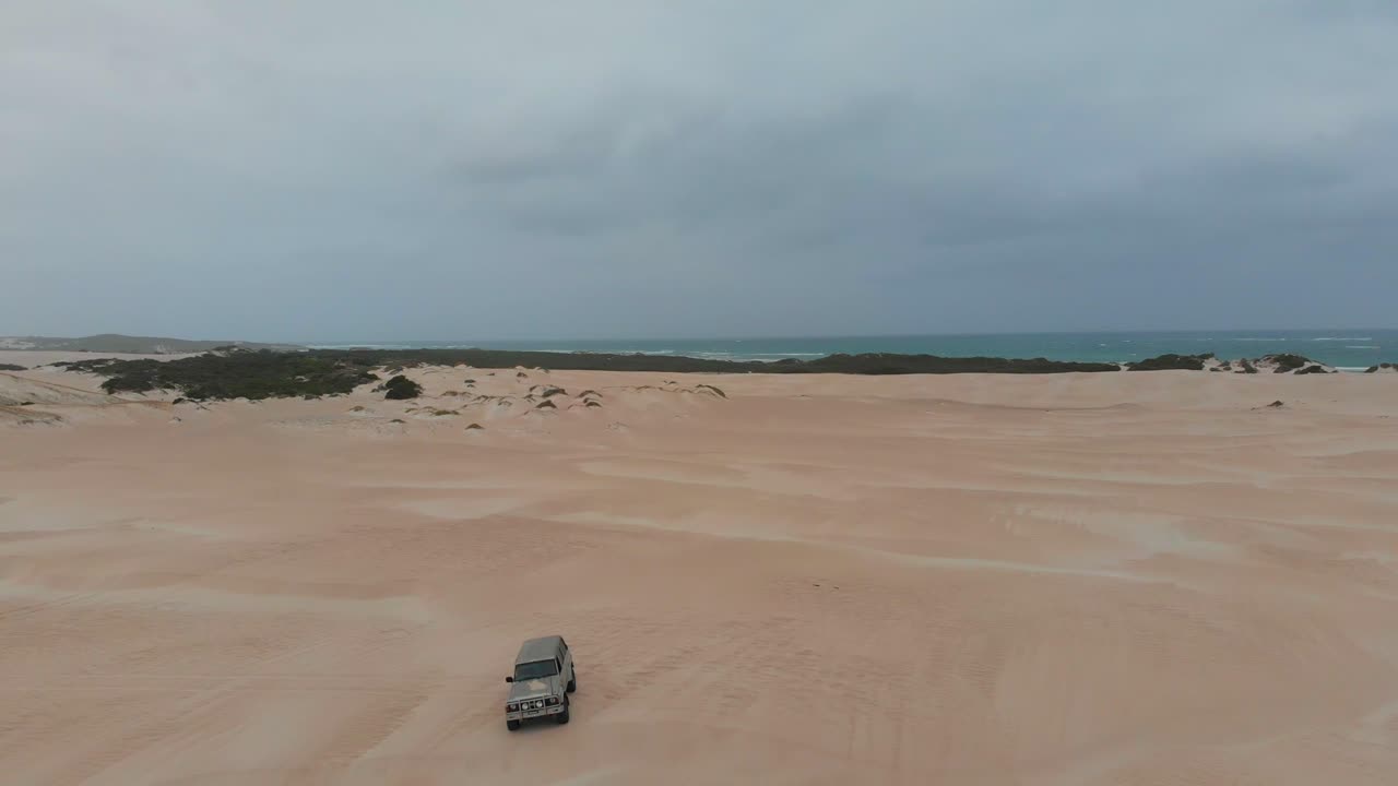 자동차가 오스트레일리아 제럴드턴 근처의 모래 언덕에서 운전하고 있습니다.