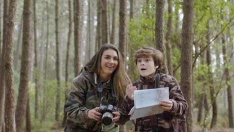 caucasian woman and her young son exploring nature wonders while walking in natural park on autumn day