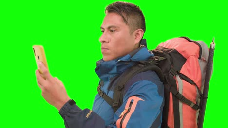 Traveler-with-yellow-smartphone-and-backpack-in-green-screen-studio