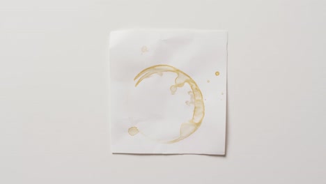 video de primer plano de un pedazo de papel con mancha de anillo de taza de café sobre un fondo blanco