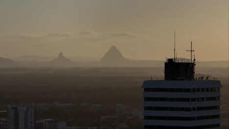 Telephoto-Parallax-Building-Rooftop-With-Mountains-On-Horizon-At-Dusk,-4K-Drone