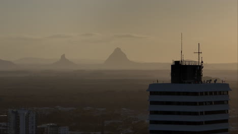 telephoto parallax building rooftop with mountains on horizon at dusk, 4k drone