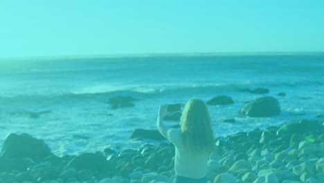 person sitting on rocky beach with colorful striped animation overlay