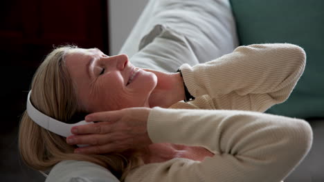 relaxing at home, senior woman enjoying music with headphones, smiling peacefully