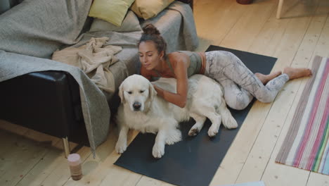 woman relaxing with her dog on a yoga mat in the living room