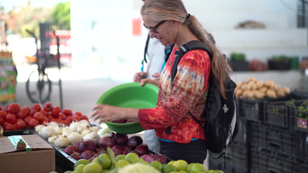 mujer madura eligiendo cebollas en un mercado de frutas y verduras al aire libre